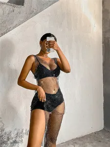 Vista detallada del vestido de malla negra con pedrería llevado por una modelo en un entorno