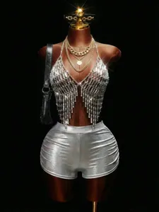 Detail van zilveren kristallen franje body chain en metallic shorts voor rave.
