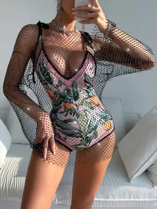 Detailed view of women's black long sleeve rhinestone fishnet dress over printed bodysuit