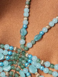 Detalle macro de cuentas acrílicas azules y verdes en una cadena de cuerpo boho