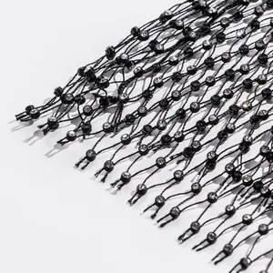 Macro detail of sparkling clear rhinestones on black elastic fishnet mesh vest fabric.