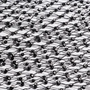 High-definition macro detail of black elastic fishnet fabric with sparkling rhinestone accents
