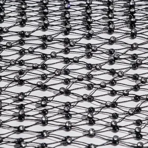 Close-up detail of black fishnet fabric with sparkling rhinestone accents for sexy vest