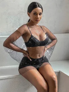 Close-up detail of black rhinestone mesh dress on model sitting against stone background