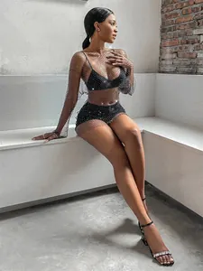 Detail of black rhinestone mesh cover-up dress worn by model in industrial setting