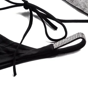 Close-up detail of black bikini bottom featuring sparkling rhinestone straps and ties