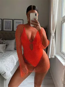 Detail view of vibrant orange long-sleeve mesh dress with sparkling rhinestone accents