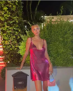 Close-up detail of a vibrant pink metallic sequin mesh mini dress worn by a model at night
