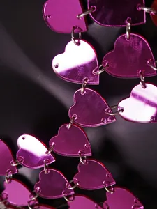 Detailansicht von rosa herzförmigen Acryl-Pailletten, die mit silbernen Metallringen verbunden sind