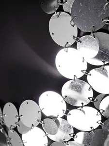 Detailaufnahme von schimmernden silbernen Metallpailletten und Kettenringen für Weste