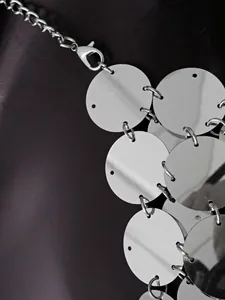 Detail von silbernen Metallpailletten und Kettengliedern für ein rückenfreies Clubwear-Top