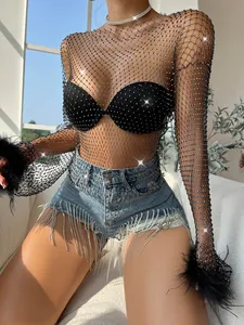 Detailed shot of black fishnet top with shimmering rhinestones and feather cuffs