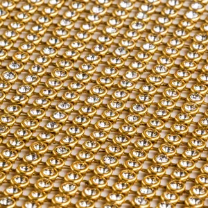 Gros plan sur le tissu maille dorée orné de strass cristallins pour robe de soirée.