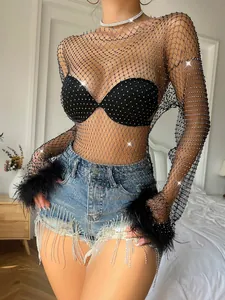 Detail showing black fishnet long sleeve top with shiny rhinestones and luxury feather cuffs.
