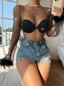 Detailed view of women's black rhinestone fishnet top with fur cuffs and mesh texture