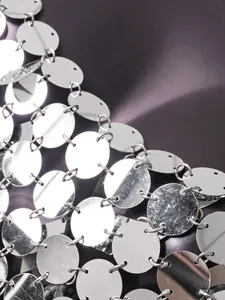 Gros plan d'un top à paillettes argentées avec des disques métalliques ronds reliés.
