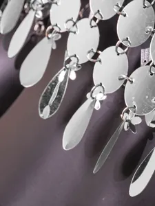 Vue macro de paillettes argentées réfléchissantes sur un haut caraco élégant pour femme.