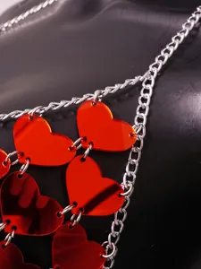 Close-up detail of sexy red acrylic hearts and silver chain links on a backless vest