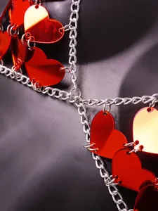 Close-up detail of red acrylic heart shapes and silver metal chain links on vest