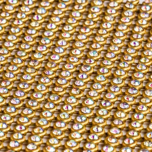 Détail macro montrant des strass irisés scintillants sur un tissu en maille dorée de qualité.