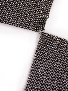 Macro detail of a glamorous black mesh top with sparkling rhinestones and a metal ring.