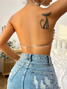 Detail of a sexy backless crop top with a fine silver chain and distressed denim.