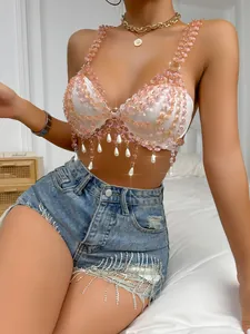 Detailed view of women's nightclub crop top with pink gemstone chains and pearls