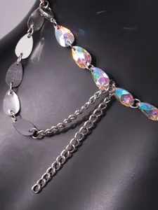 Dettaglio dei cristalli iridescenti a goccia su un top sexy a catena d'argento per discoteca