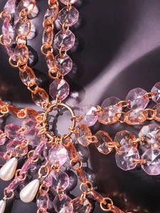 Macro view of pink faceted beads and faux pearls on a luxury gemstone body chain top