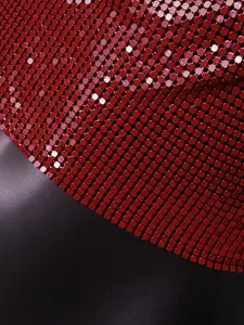 Macro detail of vibrant red metal sequins on a sexy halter top garment.