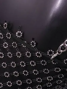 Close-up of black mesh dress with silver plum blossom rhinestone accents and chain.