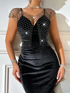 Detail shot of sparkling rhinestone fishnet overlay on black velvet evening dress.
