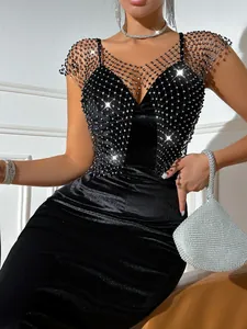 Detail of a sexy black velvet dress featuring a sparkling rhinestone fishnet mesh overlay