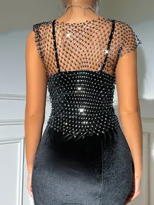 Close-up detail of a sparkly rhinestone fishnet mesh overlay on black velvet fabric back