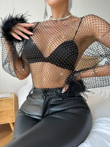 Close-up of black rhinestone fishnet top with elegant feather cuffs and sheer mesh detail.