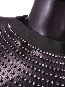 Nahaufnahme von funkelnden Strasssteinen auf einer sexy schwarzen Mesh-Weste für Damen