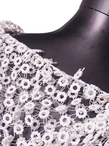 Detalle de primer plano de un vestido de flores blancas caladas con brillantes diamantes