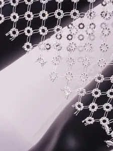 Detalle de vestido de malla blanca con motivos florales de diamantes de imitación.