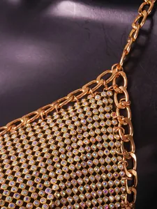 Macro detail of iridescent rhinestone mesh and gold chain on clubwear top