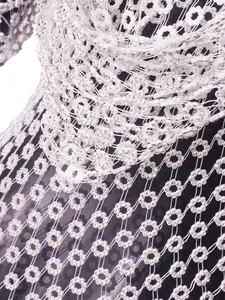 Detalle de cerca de un vestido de malla blanca con cuentas florales y pedrería brillante