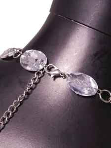Macro detail of a silver-toned body chain with elegant clear faceted faux gemstones