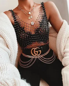 Detailed shot of a black rhinestone fishnet tank top with elegant gold necklaces.