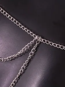 Detailed close-up view of a fashionable silver metal body chain with intricate links