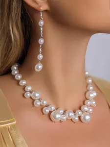 Detailaufnahme eines eleganten weißen Perlen-Chokers und passender Quasten-Ohrringe