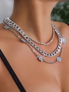 Detail einer mehrlagigen silbernen Gliederkette mit glänzenden Kristall- und Blumenanhängern.