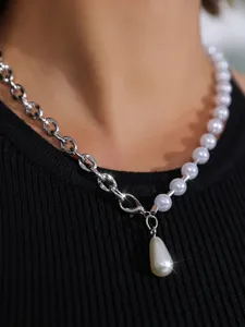 Nahaufnahme einer silbernen Gliederkette und Perlenhalskette mit einem Tropfenanhänger.