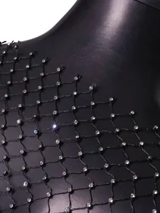 Macro detail of sparkling rhinestones on black fishnet mesh fabric for sexy beach top