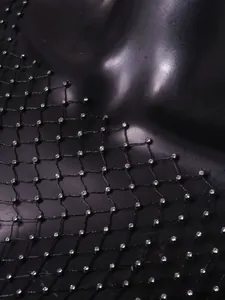 Close-up macro view of black fishnet mesh fabric embellished with sparkling rhinestones