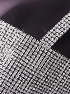 Close-up of shimmering silver rhinestone mesh fabric with metal ring strap detail