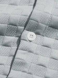Dettaglio macro del tessuto a maglia nido d'ape grigio con bottone bianco decorativo